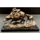 An oriental style bronze - young child on water buffalo?s back with calf pulling at buffalo?s tail.