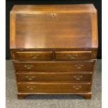 A 20th century Reprodux oak bureau, fall front enclosing pigeonholes, a small door, two short