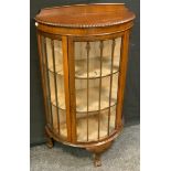 An early-mid 20th century mahogany bow front display cabinet, shaped half gallery above a glazed