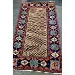 A Middle Eastern hand woven rug, geometric designs in hues of caramel, taupe and indigo on a red