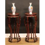 A pair of Chinese hardwood jardiniere stands, the circular top above a shaped frieze carved with