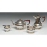 A E Jones - an Arts and Crafts silver four piece tea service, comprising teapot, hot water pot, milk
