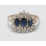 A diamond, sapphire and yellow gold coloured metal lady's ring, the shaped plateau set with three