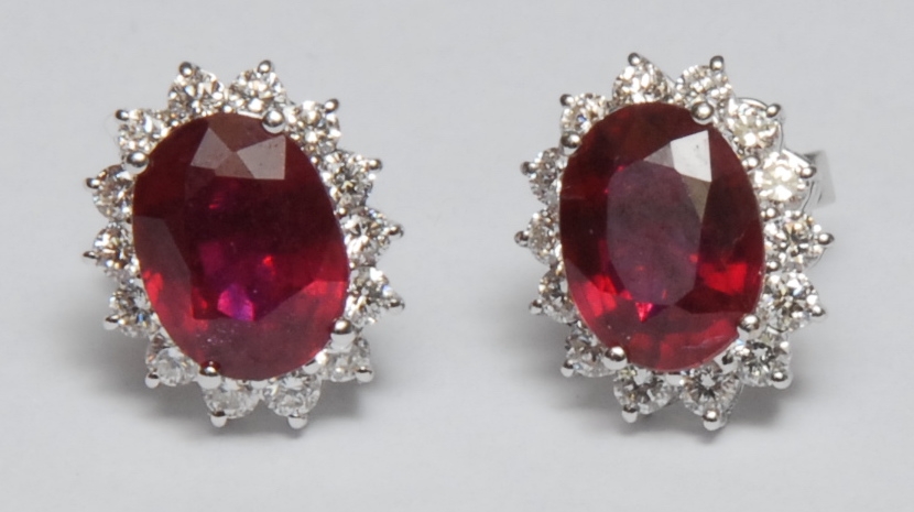 A pair of ruby and diamond cluster stud earings, mounted on 18k white gold, the oval central ruby