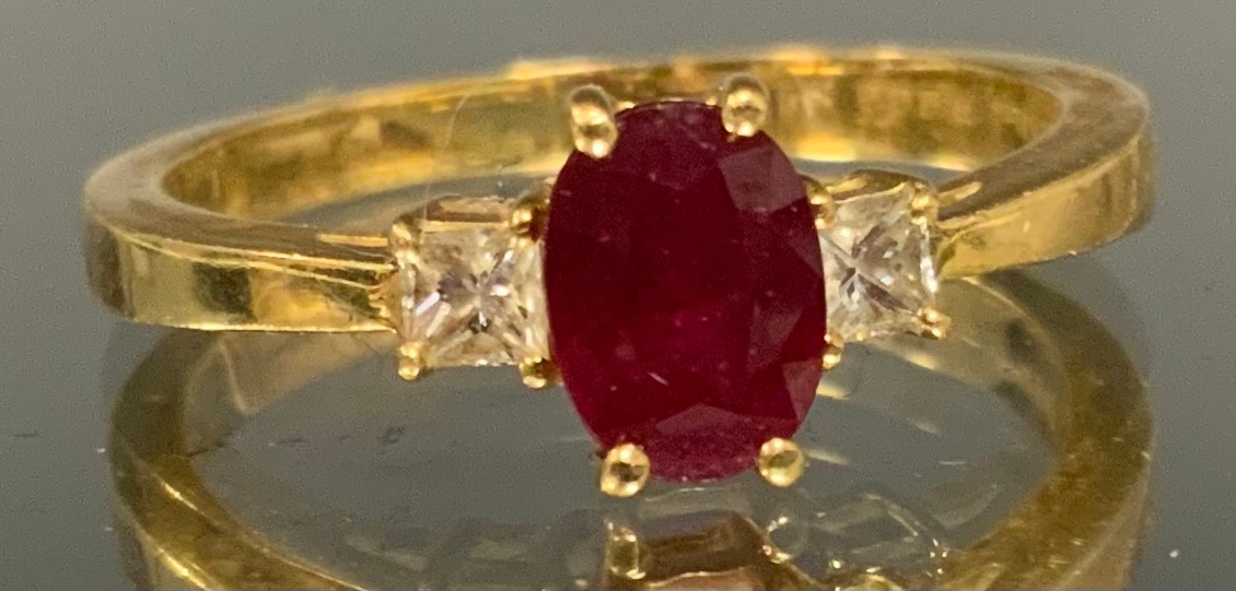 A ruby and diamond trilogy ring, central oval red ruby approx 0.50ct, flanked by a princess cut