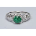 An emerald and diamond cluster ring, oval vibrant deep green emerald quarter claw set above a