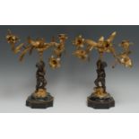 A pair of mid 19th century bronze and ormolu figural two light candleabra, the scantily clad cherubs