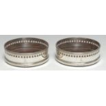 A pair of George III silver circular wine coasters, the pierced borders outlined with wrigglework,