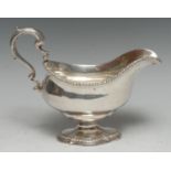 A George III cast silver pedestal sauce boat, acanthus-capped double-scroll handle, gadrooned