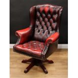 A Chesterfield style wingback swivel armchair, deep-button upholstery, scroll arms, 116cm high, 83cm