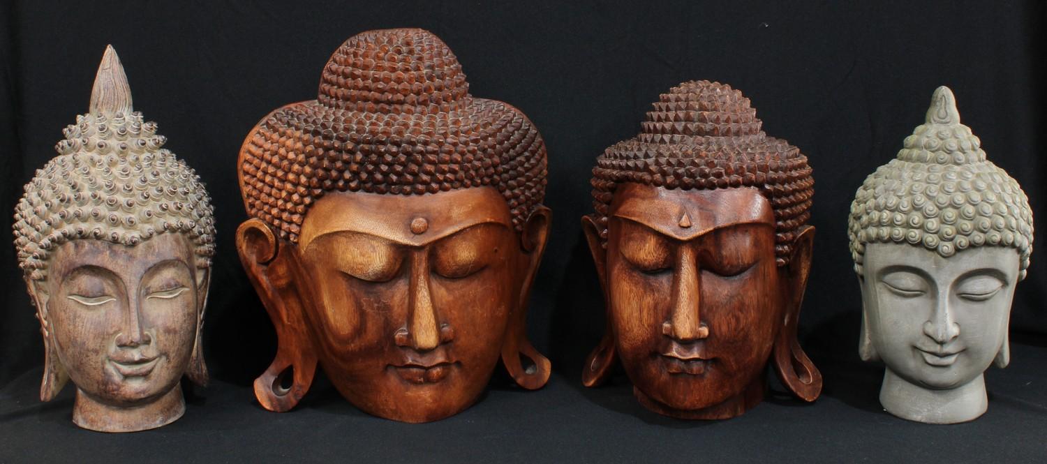 An Indonesian carved wooden bust of The Buddha, 35cm; another similar smaller, 32cm; another