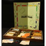 An early 20th century Monopoly set, metal playing pieces, top hat, iron, racing car, thimble,