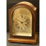 An early 20th century oak bracket clock, 13.5cm arched silvered dial, the chapter ring inscribed