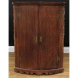 A 19th century oak bow front corner cupboard, moulded cornice above a pair of doors enclosing