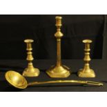 A George III brass candlestick; another pair, Victorian; a large brass ladle (4)