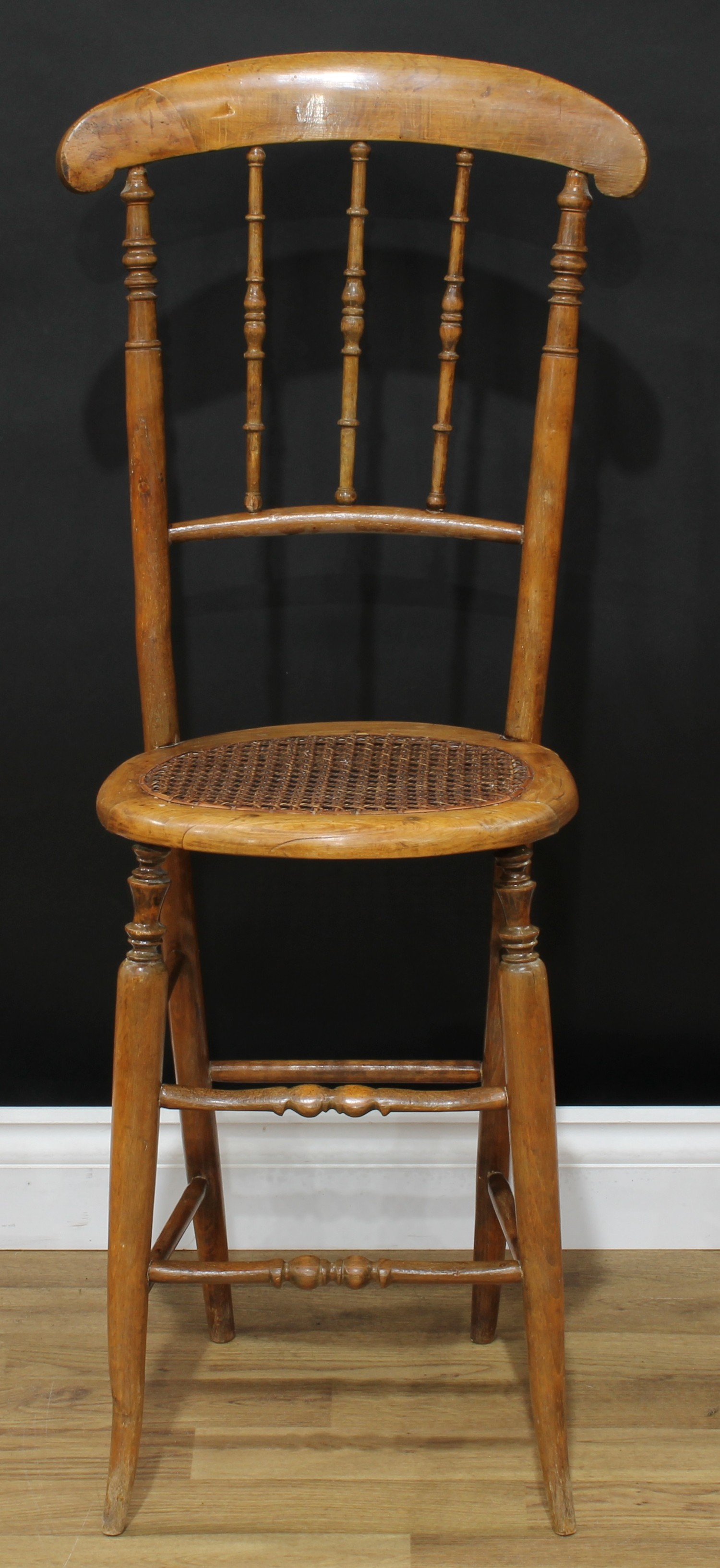 A Victorian beech child's correction chair, curved cresting rail, turned spindle back, oval cane