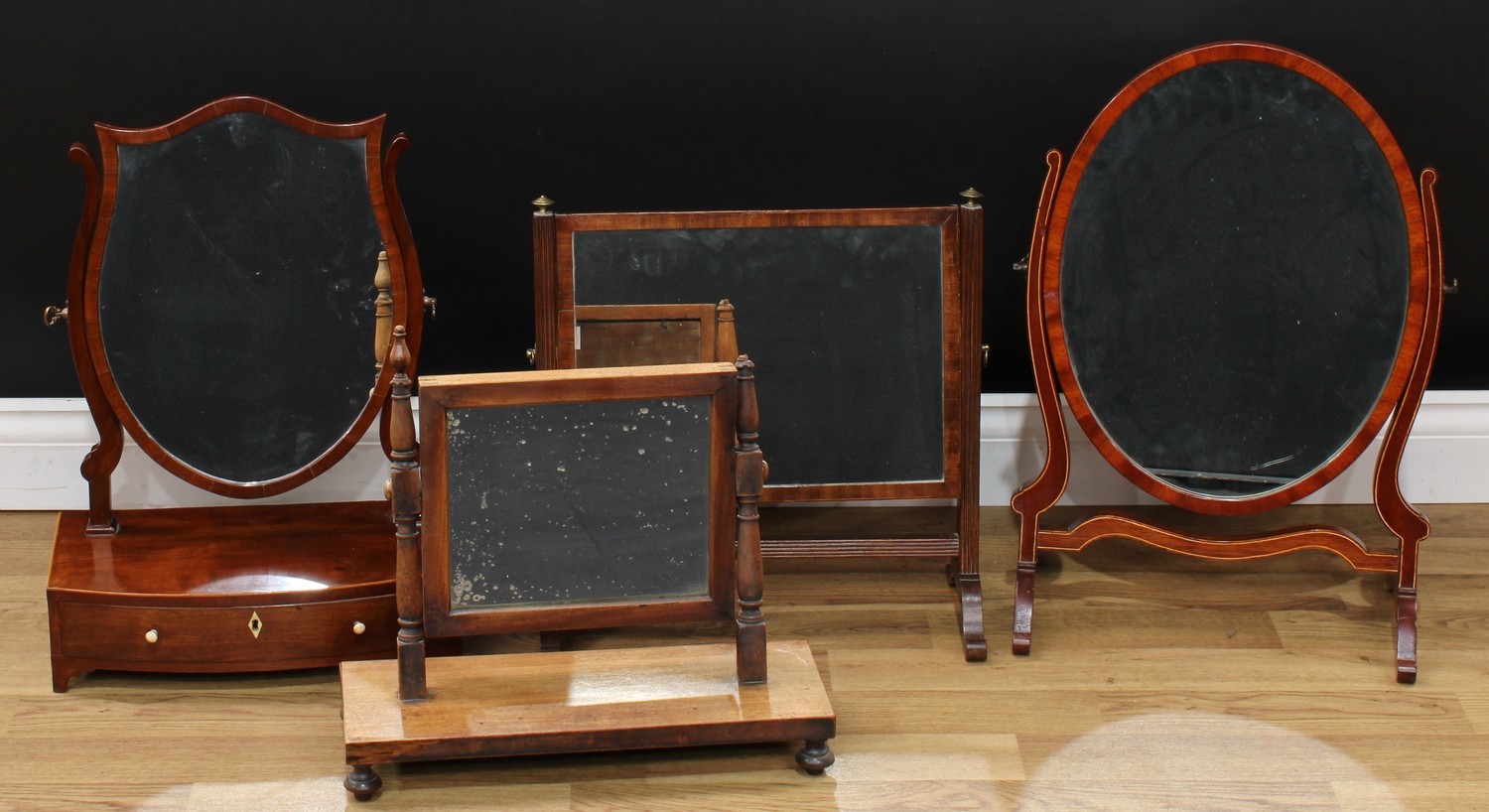 A George III Revival mahogany shield-shaped dressing mirror, the bowed base with a long drawer,