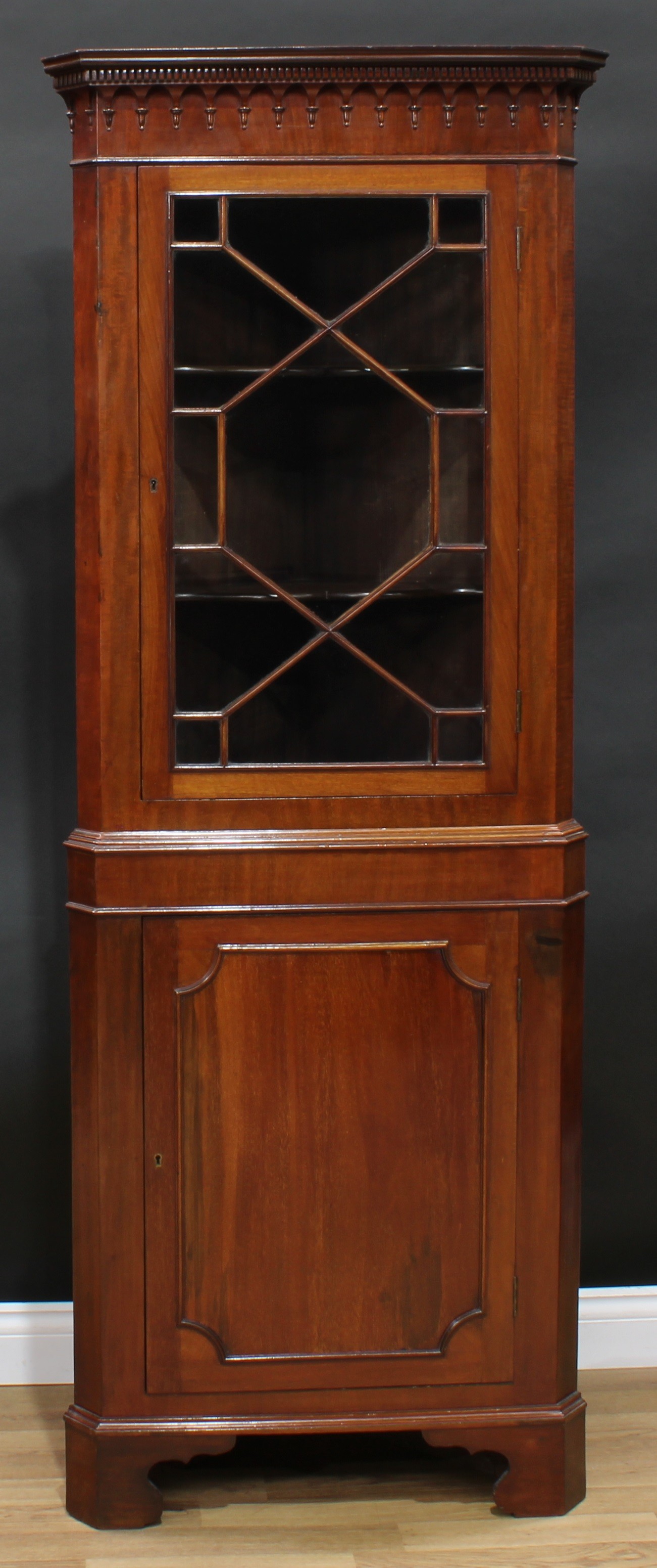 A George III Revival mahogany floor standing corner display cabinet, dentil cornice above a glazed