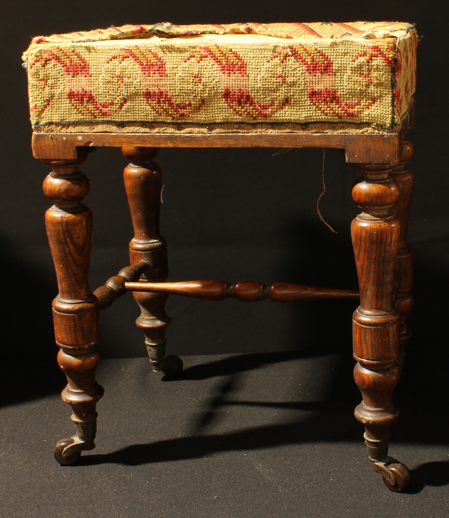 An oak footstool, woolwork tapestry upholstery, turned legs, ceramic casters, 45cm high, c.1900