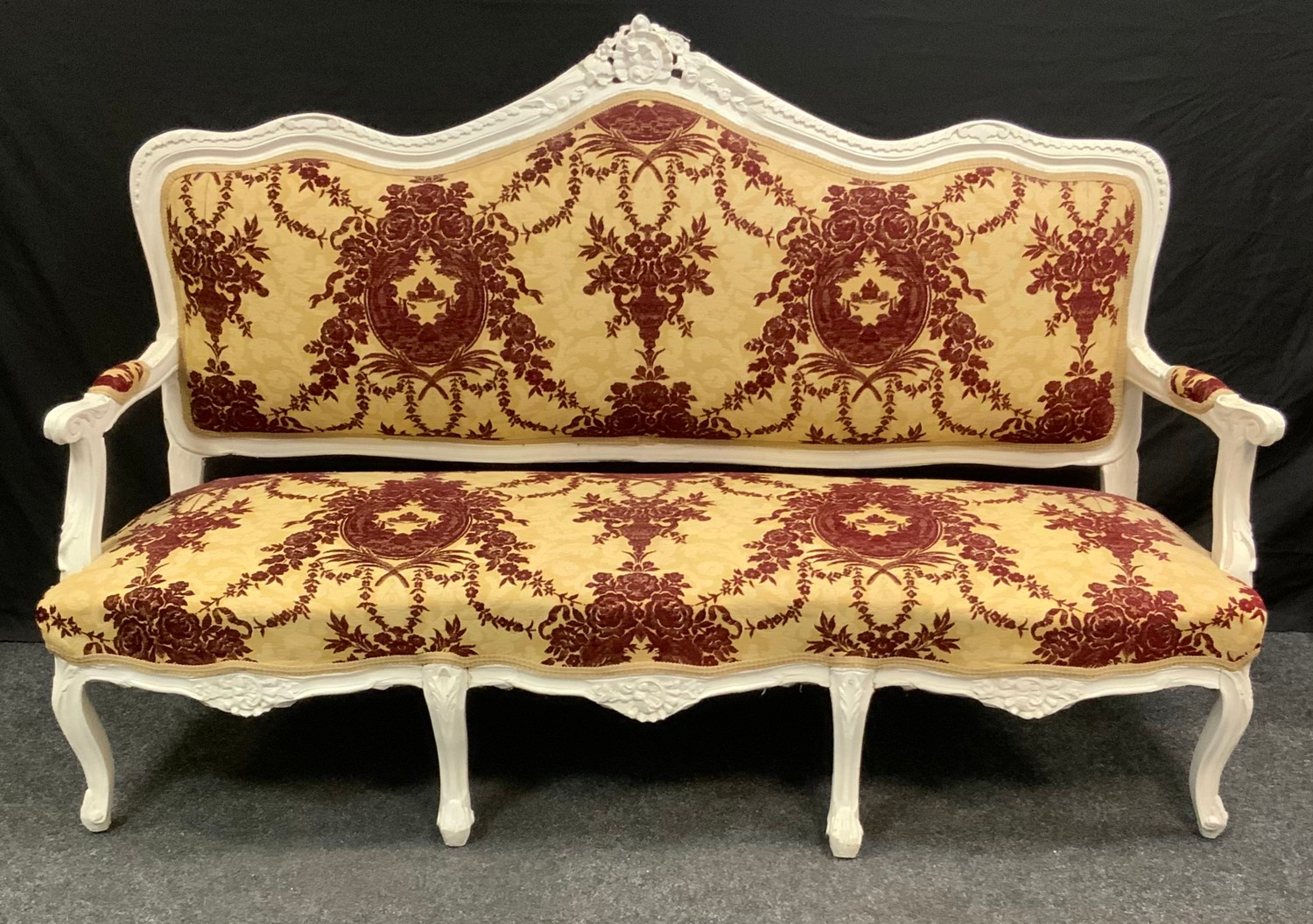 A Victorian painted three-seat salon sofa, shaped and carved cresting rail, stuffed over upholstery,