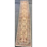 A Persian hand-made Tabriz runner decorated with foliage in hues of red, salmon pink and taupe on an