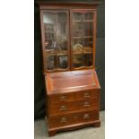 An Art Nouveau mahogany bureau bookcase, outswept cornice above a pair of glazed doors, fall front