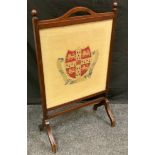 An early 20th century oak rectangular fire screen, turned finials, the tapestry banner with