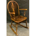 A mid 20th century wheelback rocking chair, saddle seat, 93cm high.