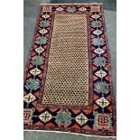 A Middle Eastern hand woven rug, geometric designs in hues of caramel, taupe and indigo on a red