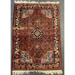 A Persian hand-made Bidjar rug decorated in hues of tangerine, steel blue and cobalt on a brick