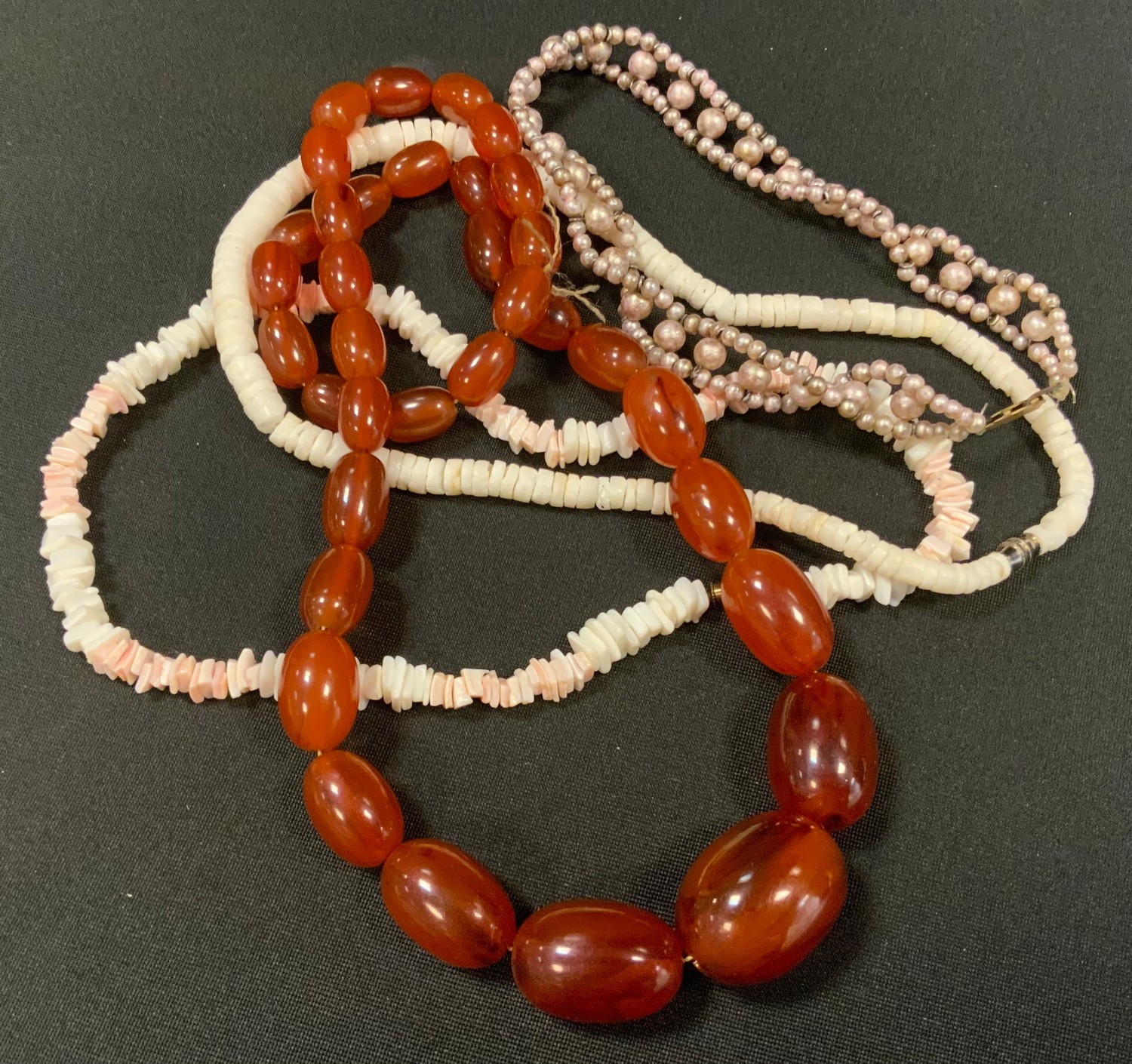 An amber coloured graduated bead single strand necklace; a coral necklace; etc