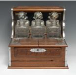 A late Victorian/Edwardian oak tantalus cabinet, the three hobnail decanters with prismatic