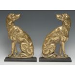 A pair of brass and cast iron door stops, each cast as seated dog, facing to dexter and sinister,