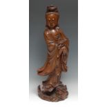 A large Chinese hardwood figure, carved as Guanyin, she stands upon a dragon, holding beads and a