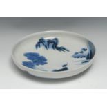 A Japanese circular dish, painted in tones of underglaze blue with a figure in a monumental