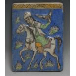 A Persian rectangular tile, moulded and painted in the typical Qajar taste with a falcolner on