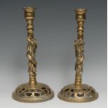 A pair of Chinese gilt brass candlesticks, each pillar cast with a dragon, conforming pierced bases,