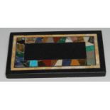 A pietra dura rectangular desk weight, the field inlaid with a band of turquoise, lapis lazuli,