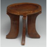 Tribal Art - an African stool, dished circular top above four curved legs, carved with borders of