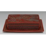 A Chinese cinnabar lacquer rectangular box, cover and stand, in relief with figures and pagodas in a