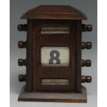 An early 20th century oak perpetual desk calendar, sarcophagus cresting above glazed apertures for