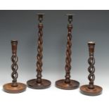 A pair of substantial turned oak candlesticks, cast leafy C-scroll sconces above Solomonic
