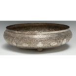 An Indian silver coloured metal circular bowl, chased with dense scrolling foliage and lozenge