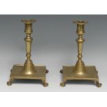 A pair of Spanish brass table candlesticks, campana sconces with broad rims, scroll feet, 20cm high,