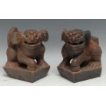 A pair of Chinese carvings, of temple lions, picked-out in tones of red, 16cm high