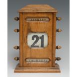An early 20th century oak perpetual desk calendar, sarcophagus cresting above glazed apertures for