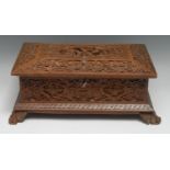 An Indian/Burmese hardwood sarcophagus table box, carved with deities, peacocks and scrolling