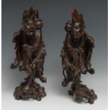 A pair of Chinese hardwood carvings, of emaciated elders, wearing flowing robes, each holding a