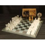 A carved wooden chess set in a wooden box with sliding cover; a glass chess set and board; a glass