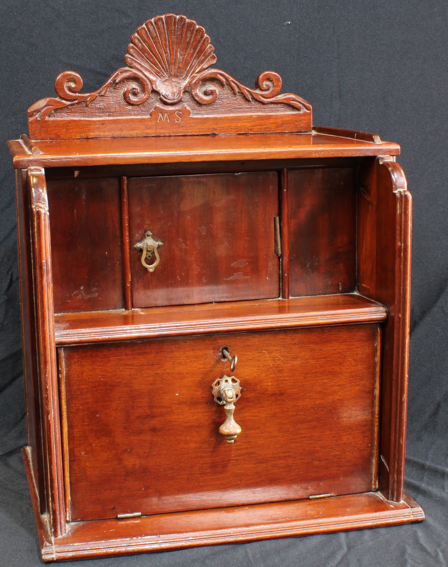 An early 20th century mahogany desk top cabinet, shaped cresting above an open niche and fall front,